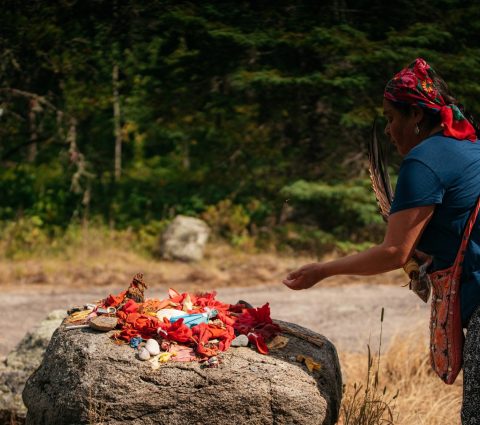 A sacred offering is laid out on a rock by a person performing a blessing.