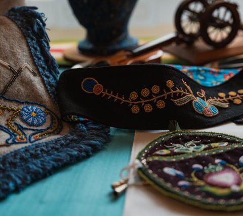 Intricately embroidered textiles and accessories, showcasing vibrant patterns and craftsmanship on a colourful surface.