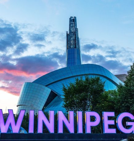 Winnipeg sign in front of  the Canadian Museum for Human Rights at sunset